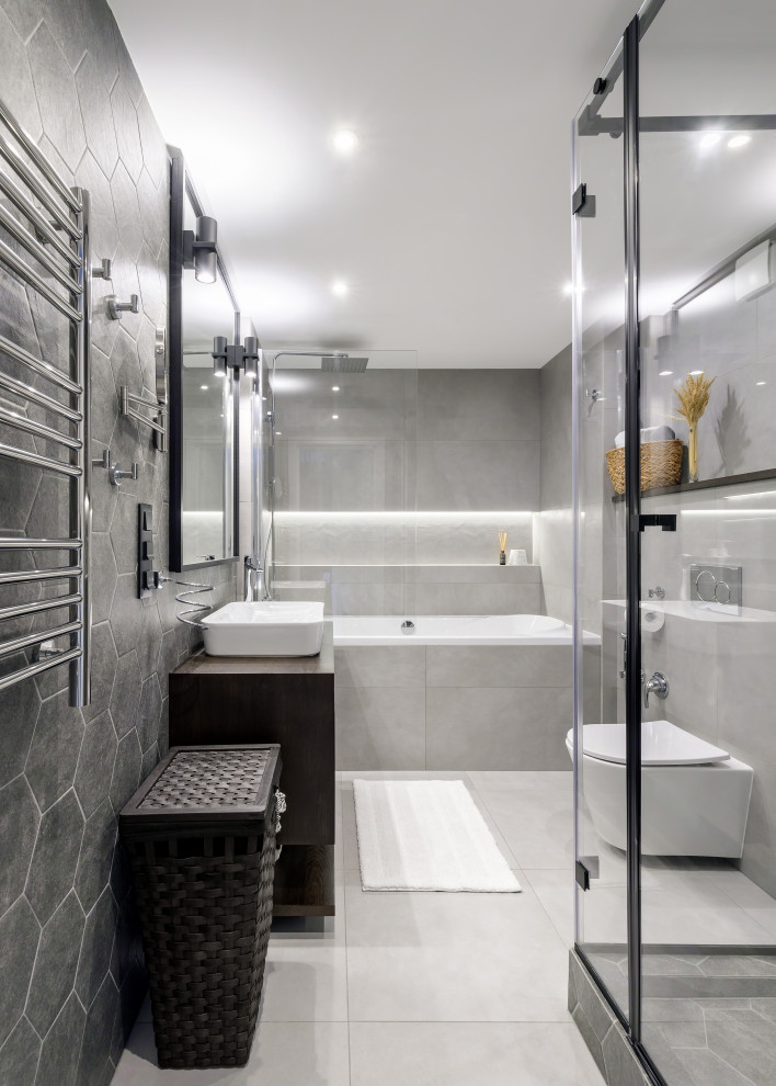 This is an example of a medium sized contemporary shower room bathroom in Saint Petersburg with flat-panel cabinets, dark wood cabinets, an alcove bath, a corner shower, a wall mounted toilet, grey tiles, porcelain tiles, grey walls, porcelain flooring, a built-in sink, wooden worktops, grey floors, brown worktops, an enclosed toilet, a single sink, a floating vanity unit and a hinged door.