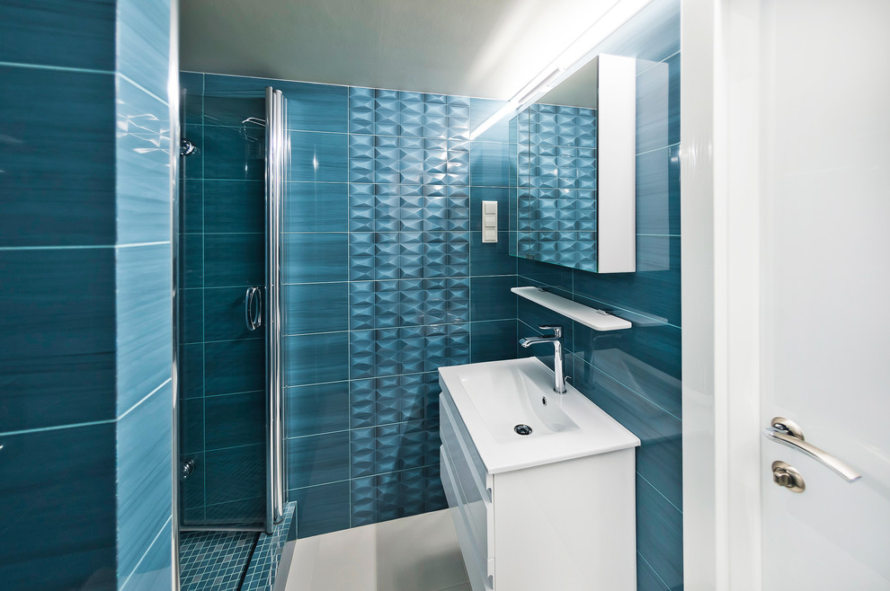 Diseño de cuarto de baño actual con puertas de armario blancas, baldosas y/o azulejos de cerámica, suelo de baldosas de porcelana, aseo y ducha, armarios con paneles lisos, ducha empotrada, baldosas y/o azulejos azules y lavabo integrado