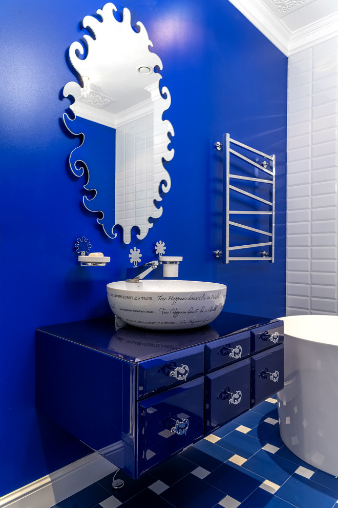 Klassisk inredning av ett blå blått en-suite badrum, med blå skåp, ett fristående badkar, blå väggar, ett fristående handfat och blått golv