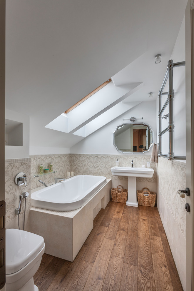 Imagen de cuarto de baño principal tradicional con bañera encastrada, baldosas y/o azulejos beige, paredes blancas, lavabo con pedestal y suelo marrón