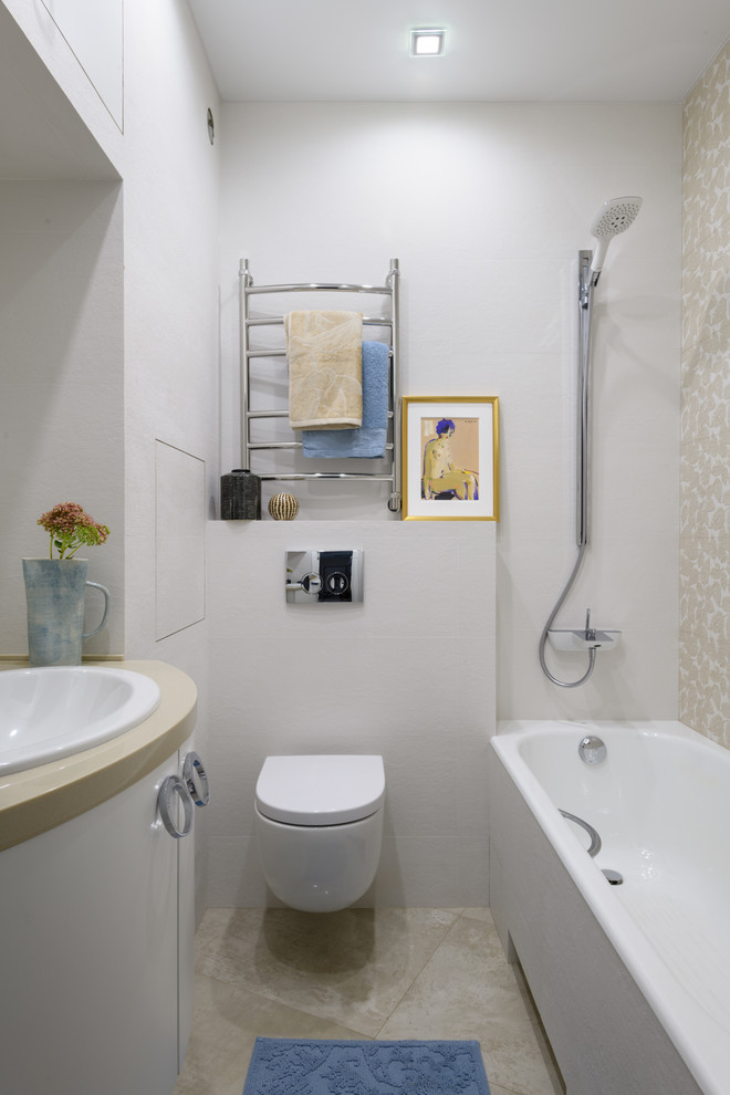 На фото: главная ванная комната в современном стиле с плоскими фасадами, белыми фасадами, ванной в нише, душем над ванной, инсталляцией, накладной раковиной, бежевым полом и бежевой столешницей с