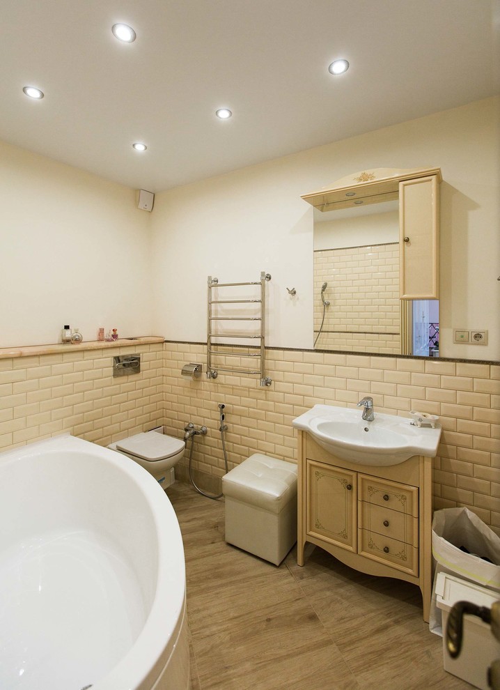 На фото: ванная комната в классическом стиле с угловой ванной, душем над ванной, инсталляцией, бежевой плиткой, белыми стенами и монолитной раковиной с