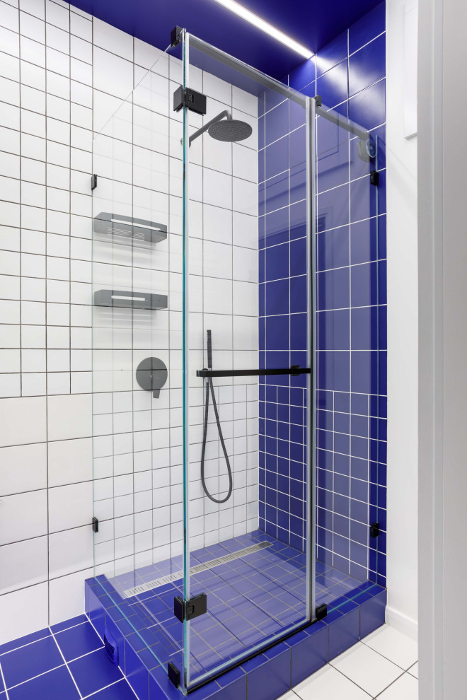 Foto di una stanza da bagno minimal con doccia ad angolo, piastrelle blu, piastrelle bianche, pavimento bianco e porta doccia a battente
