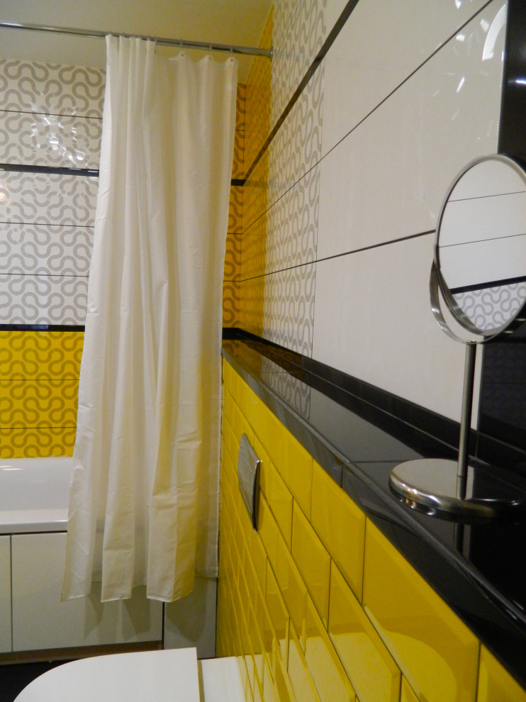 Inspiration för mellanstora moderna vitt en-suite badrum, med släta luckor, vita skåp, ett fristående badkar, en dusch/badkar-kombination, en vägghängd toalettstol, flerfärgad kakel, keramikplattor, flerfärgade väggar, klinkergolv i porslin, ett väggmonterat handfat, bänkskiva i akrylsten, svart golv och dusch med duschdraperi