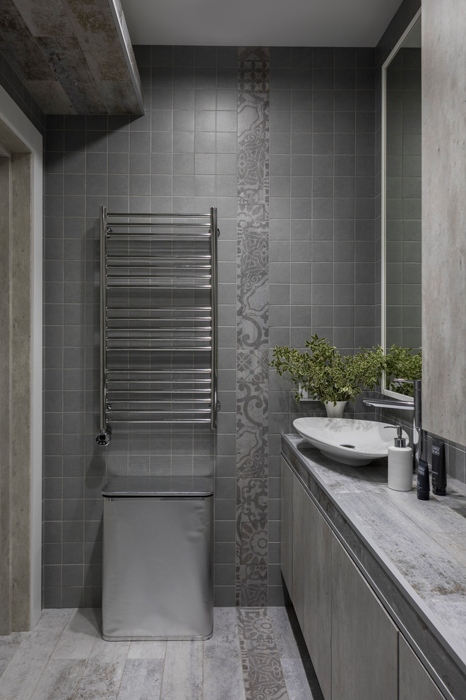 Bild på ett funkis grå grått badrum, med släta luckor, grå kakel, ett fristående handfat och grått golv