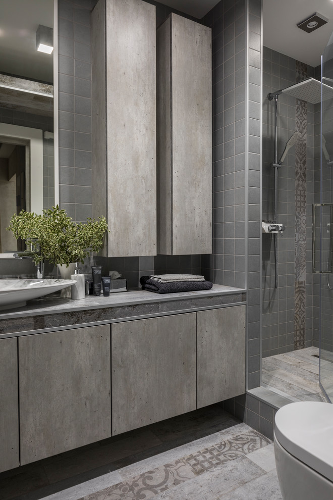 Idées déco pour une salle de bain contemporaine avec un placard à porte plane, des portes de placard grises, un carrelage gris, une vasque, un sol gris, une cabine de douche à porte battante et un plan de toilette gris.