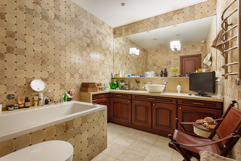 Foto på ett stort vintage en-suite badrum, med luckor med infälld panel, bruna skåp, beige kakel, marmorkakel, beige väggar, klinkergolv i keramik, ett fristående handfat, bänkskiva i akrylsten och en toalettstol med separat cisternkåpa