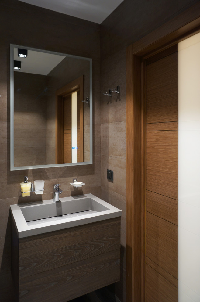 Источник вдохновения для домашнего уюта: маленькая ванная комната в современном стиле с плоскими фасадами, коричневыми фасадами, душем в нише, инсталляцией, коричневой плиткой, керамической плиткой, коричневыми стенами, полом из керамогранита, душевой кабиной, монолитной раковиной, столешницей из искусственного камня, коричневым полом, душем с распашными дверями, серой столешницей, тумбой под одну раковину и подвесной тумбой для на участке и в саду