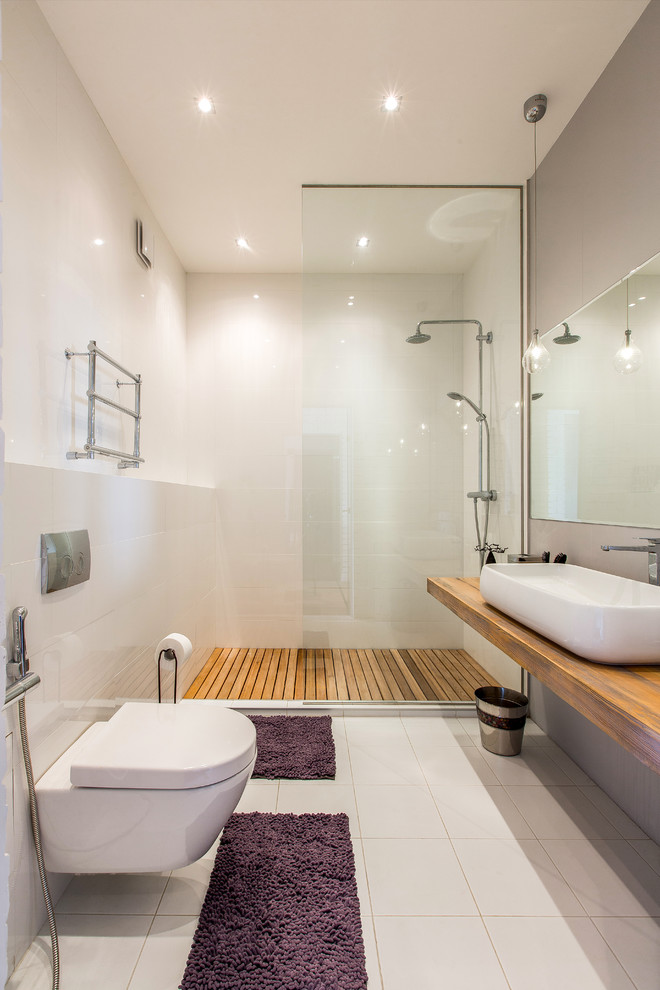 Idéer för mellanstora funkis brunt badrum med dusch, med en vägghängd toalettstol, vit kakel, porslinskakel, vita väggar, klinkergolv i porslin, träbänkskiva, en dusch i en alkov, ett fristående handfat och med dusch som är öppen