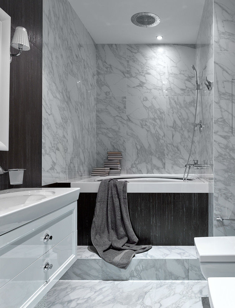 На фото: главная ванная комната в современном стиле с плоскими фасадами, белыми фасадами, полновстраиваемой ванной, душем над ванной, серой плиткой, мраморной плиткой, мраморным полом, монолитной раковиной и серым полом