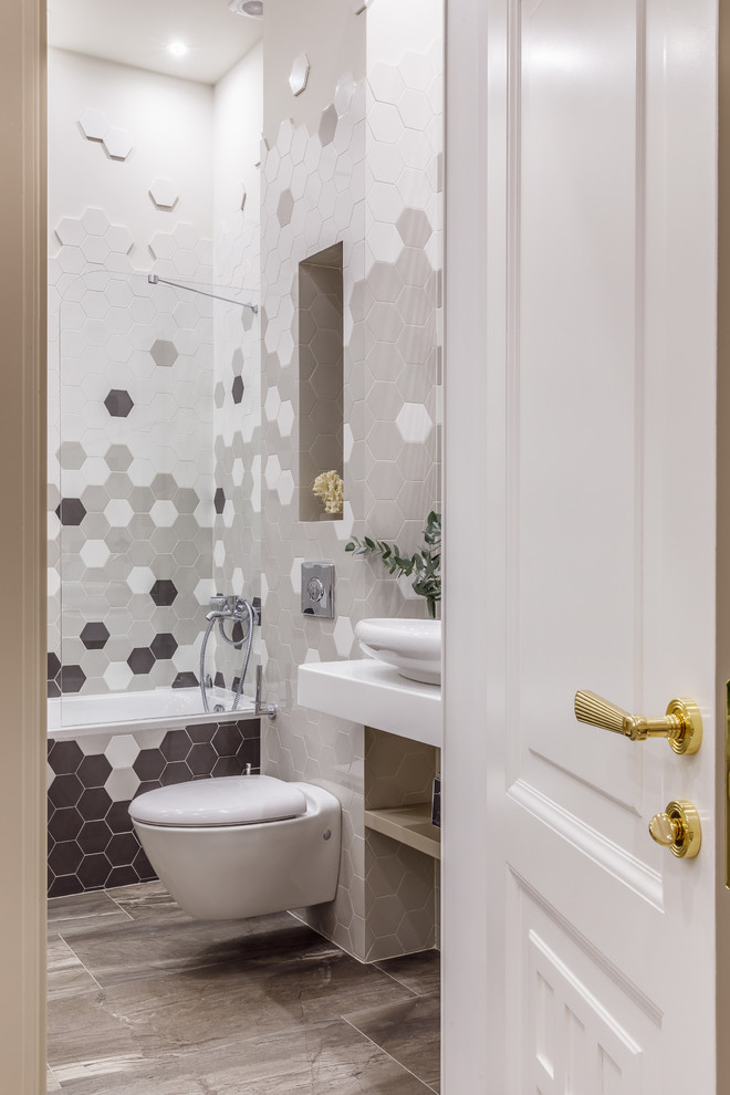 Idéer för att renovera ett funkis vit vitt en-suite badrum, med öppna hyllor, ett badkar i en alkov, en dusch/badkar-kombination, en vägghängd toalettstol, vit kakel, grå kakel, ett fristående handfat och grått golv