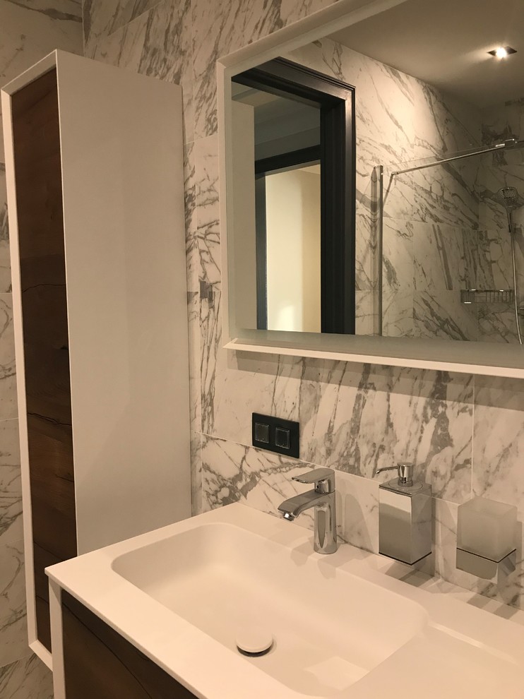 Example of a trendy black and white tile and porcelain tile marble floor and white floor alcove shower design in Moscow with flat-panel cabinets, brown cabinets, an undermount tub, a wall-mount toilet, a drop-in sink, solid surface countertops, a hinged shower door and white countertops