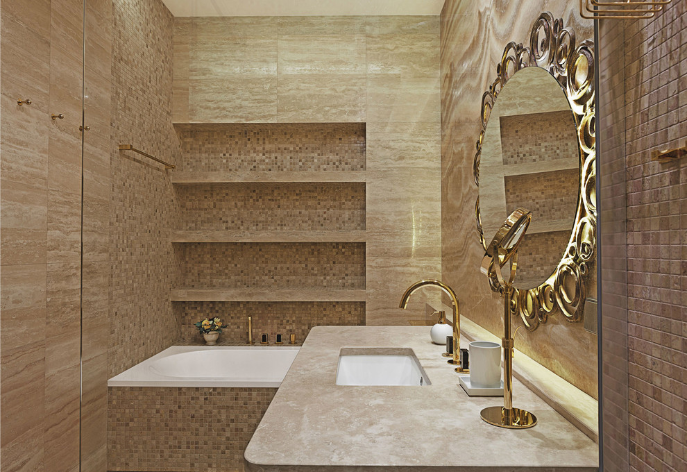 Cette image montre une salle de bain principale design avec une baignoire posée, un carrelage beige, un mur beige, un lavabo encastré et un plan de toilette en surface solide.