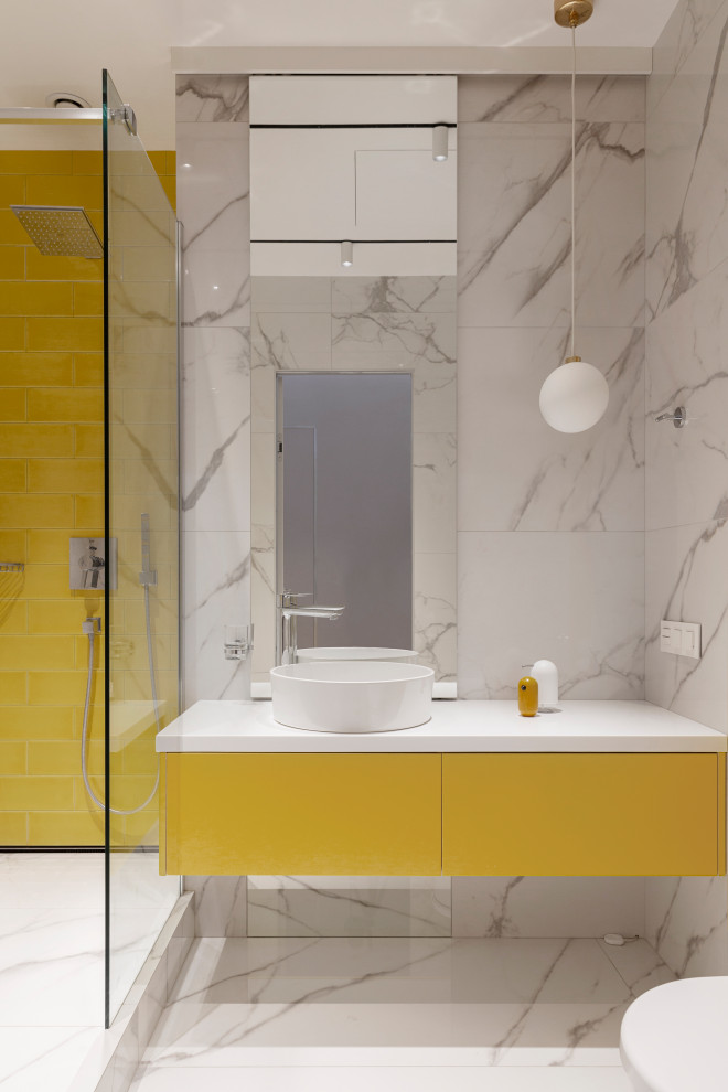 На фото: ванная комната в современном стиле с плоскими фасадами, желтыми фасадами, душем в нише, белой плиткой, душевой кабиной, настольной раковиной, белым полом и белой столешницей с