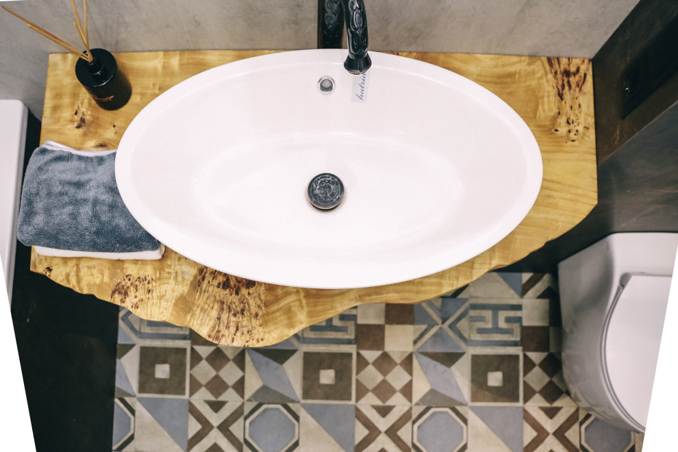 Industriell inredning av ett mellanstort gul gult en-suite badrum, med ett badkar i en alkov, en öppen dusch, en vägghängd toalettstol, grå kakel, porslinskakel, grå väggar, klinkergolv i porslin, ett nedsänkt handfat, träbänkskiva, flerfärgat golv och med dusch som är öppen