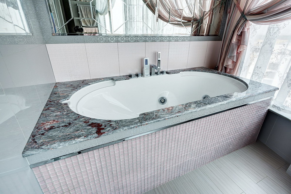 Klassisk inredning av ett badrum, med ett undermonterat badkar, rosa kakel och mosaik