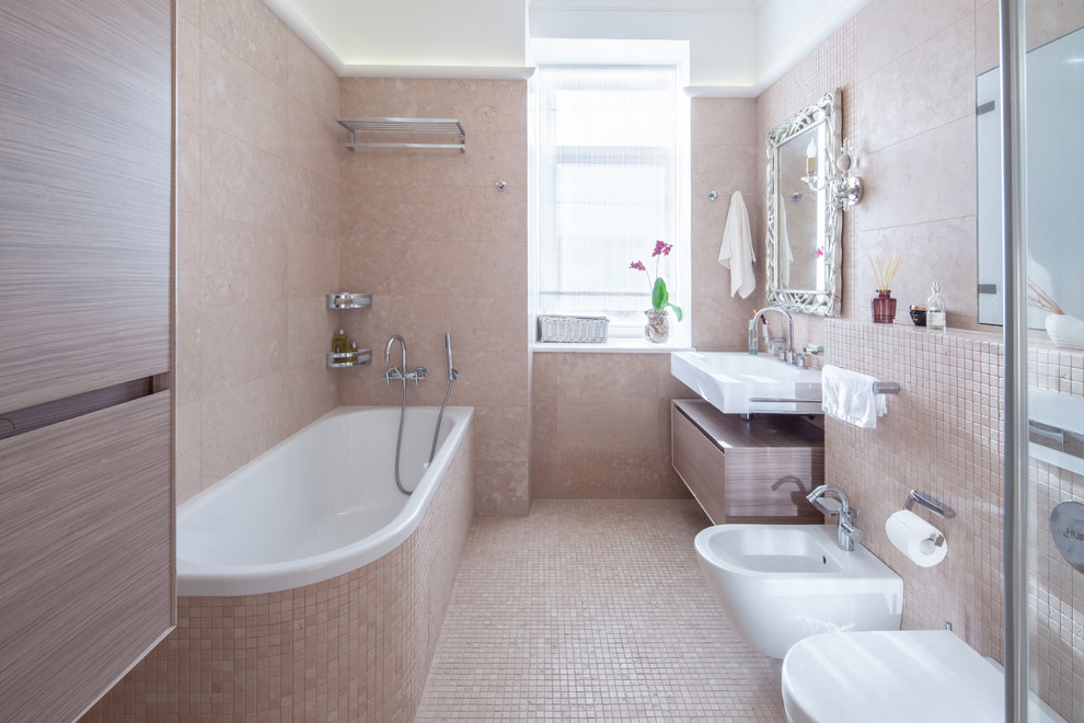 Inredning av ett modernt mellanstort en-suite badrum, med släta luckor, skåp i mellenmörkt trä, ett platsbyggt badkar, en vägghängd toalettstol, rosa kakel, stenkakel, marmorgolv, bänkskiva i akrylsten, ett väggmonterat handfat och en dusch/badkar-kombination