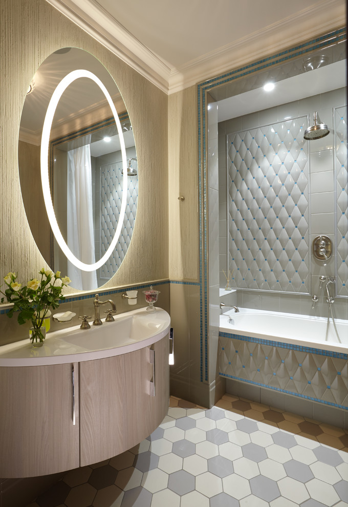 Стильный дизайн: ванная комната среднего размера в классическом стиле с плоскими фасадами, серой плиткой, бежевой плиткой, керамической плиткой, полом из керамической плитки, монолитной раковиной, светлыми деревянными фасадами, ванной в нише, душем над ванной, раздельным унитазом, бежевыми стенами и зеркалом с подсветкой - последний тренд