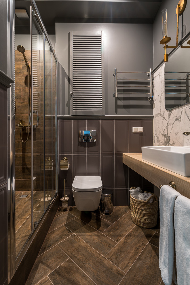 Exemple d'une salle de bain chic avec WC suspendus, un carrelage marron, un mur gris, une vasque, un sol marron, une cabine de douche à porte coulissante et un plan de toilette beige.