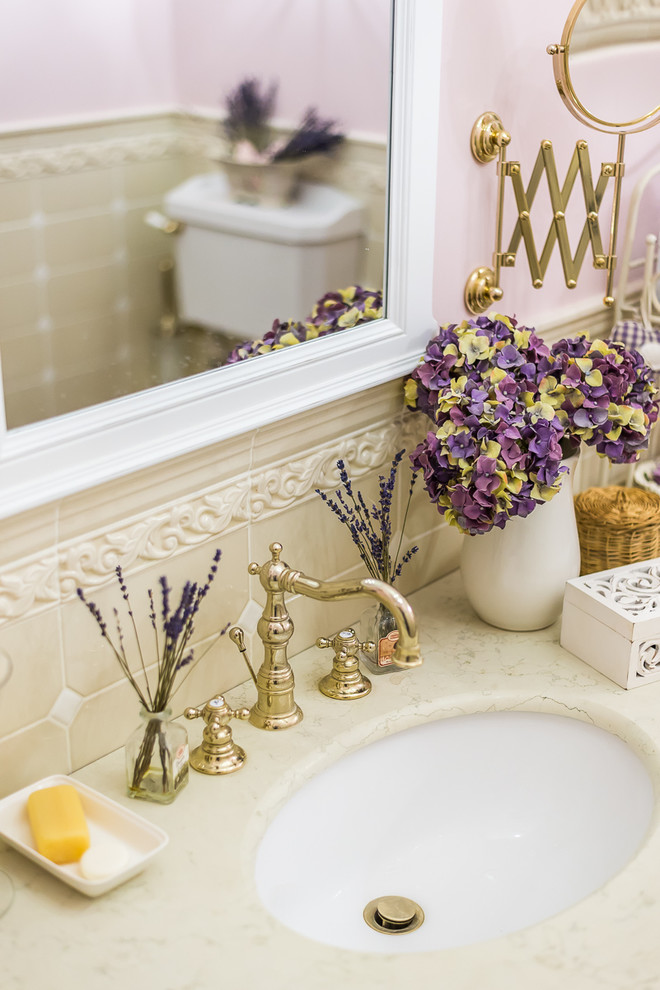 Cette image montre une salle de bain traditionnelle de taille moyenne avec un carrelage beige, un mur rose et un lavabo encastré.