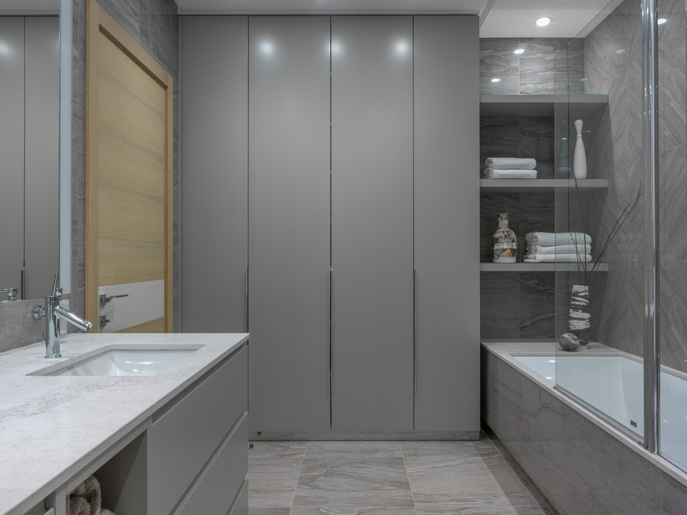 На фото: большая главная ванная комната в скандинавском стиле с плоскими фасадами, серыми фасадами, серой плиткой, серым полом, полновстраиваемой ванной, душем над ванной, врезной раковиной и серой столешницей с