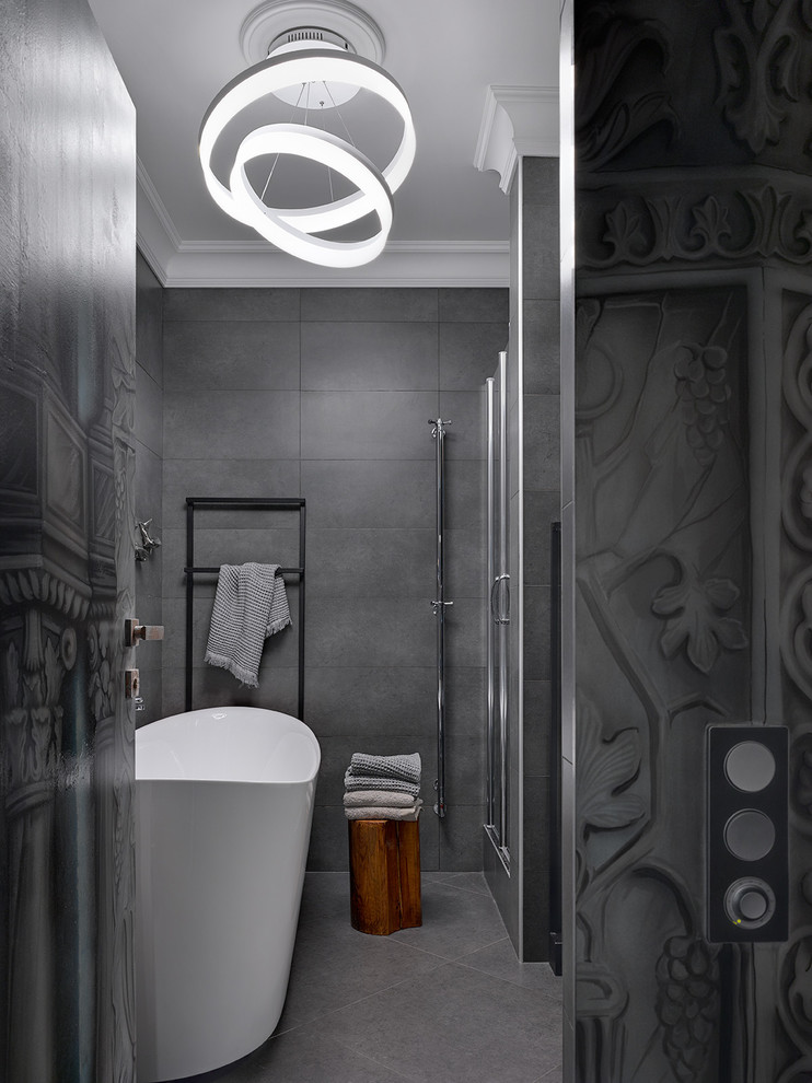 На фото: ванная комната в современном стиле с отдельно стоящей ванной, серой плиткой и серым полом с