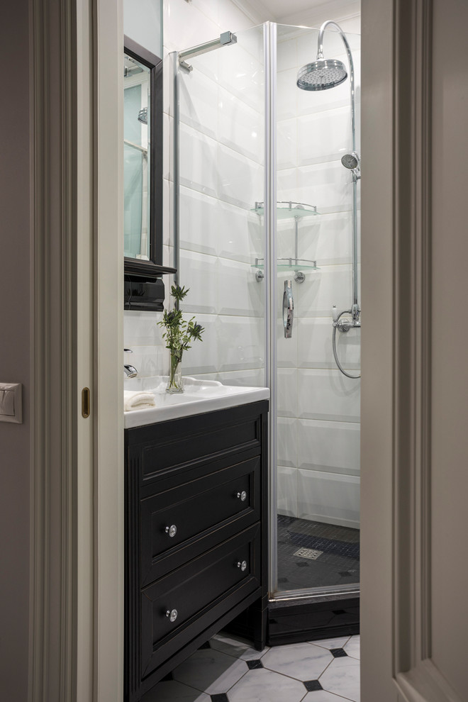 Aménagement d'une petite salle d'eau classique avec des portes de placard noires, une douche d'angle, un carrelage blanc, une cabine de douche à porte battante, un sol multicolore, un plan de toilette blanc et un placard avec porte à panneau encastré.