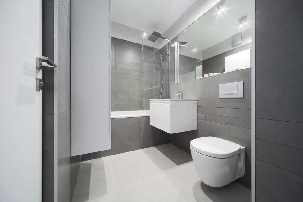 Стильный дизайн: главная ванная комната среднего размера в современном стиле с плоскими фасадами, белыми фасадами, душем над ванной, инсталляцией, серыми стенами, ванной в нише, серой плиткой, полом из керамогранита и серым полом - последний тренд