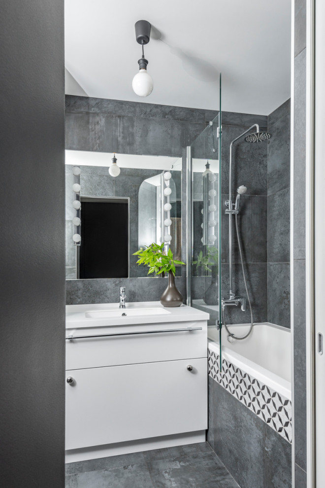 Modern inredning av ett mellanstort vit vitt badrum med dusch, med släta luckor, vita skåp, grå kakel, porslinskakel, klinkergolv i porslin, ett integrerad handfat och grått golv