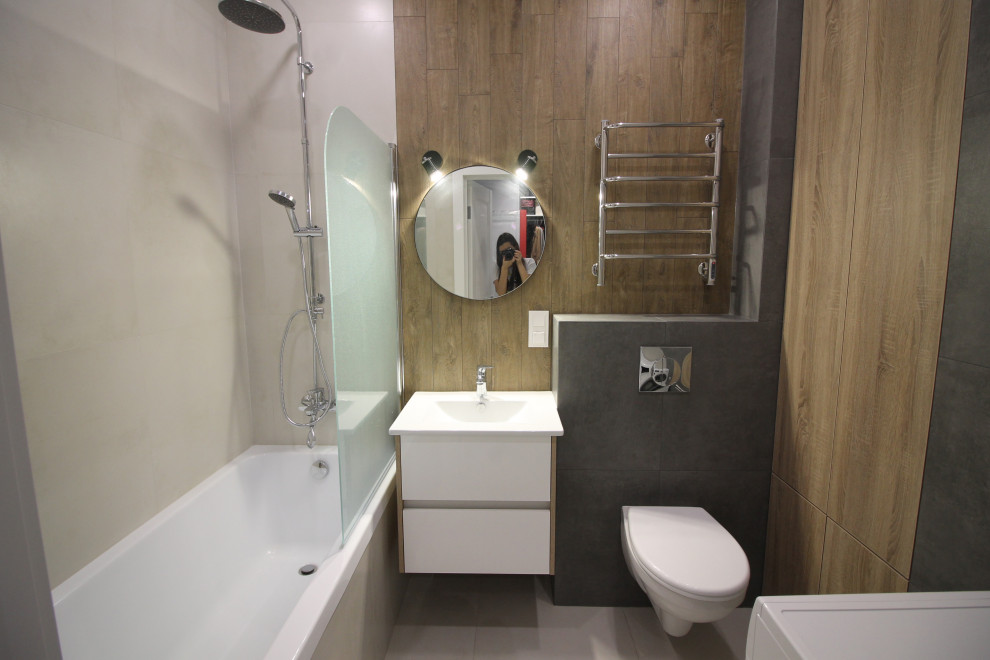Стильный дизайн: маленькая ванная комната в скандинавском стиле с плоскими фасадами, белыми фасадами, полновстраиваемой ванной, душем над ванной, инсталляцией, серой плиткой, керамогранитной плиткой, серыми стенами, полом из керамогранита, накладной раковиной, серым полом, душем с распашными дверями и белой столешницей для на участке и в саду - последний тренд