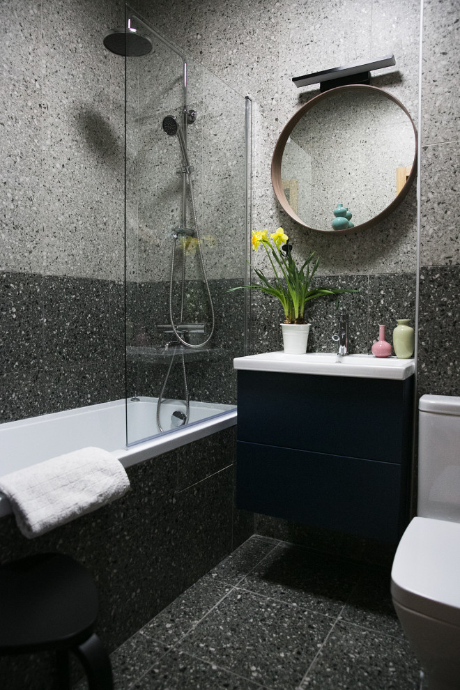 Источник вдохновения для домашнего уюта: маленькая главная ванная комната в скандинавском стиле с плоскими фасадами, синими фасадами, полновстраиваемой ванной, душем над ванной, унитазом-моноблоком, серой плиткой, керамогранитной плиткой, серыми стенами, полом из керамогранита, подвесной раковиной, столешницей из искусственного камня, серым полом, открытым душем, белой столешницей, тумбой под одну раковину и подвесной тумбой для на участке и в саду