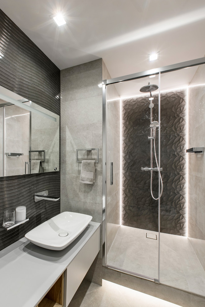 Modernes Duschbad mit flächenbündigen Schrankfronten, grauen Schränken, Duschnische, grauen Fliesen, schwarzen Fliesen, Aufsatzwaschbecken, grauem Boden und grauer Waschtischplatte in Los Angeles