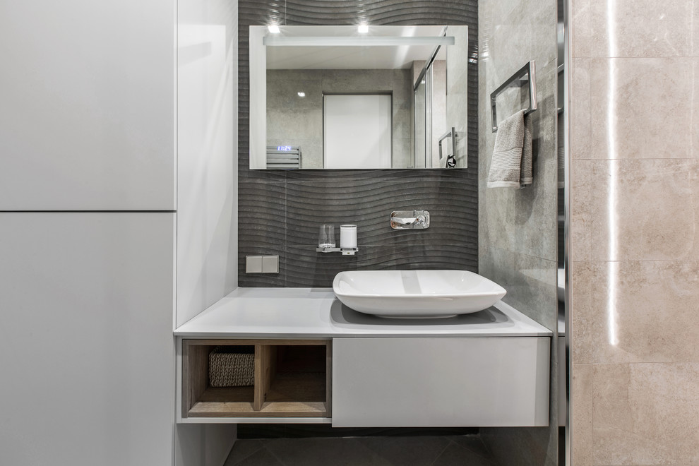Пример оригинального дизайна: ванная комната в современном стиле с плоскими фасадами, серыми фасадами, серой плиткой, черной плиткой, настольной раковиной и серой столешницей