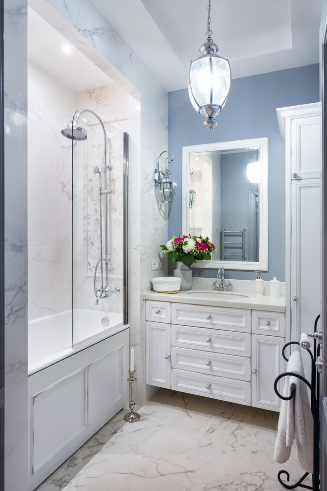 Стильный дизайн: главная ванная комната в стиле неоклассика (современная классика) с фасадами с утопленной филенкой, белыми фасадами, ванной в нише, душем над ванной, синей плиткой, синими стенами, врезной раковиной и белым полом - последний тренд