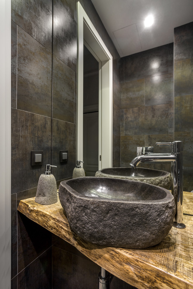 Ejemplo de cuarto de baño contemporáneo con baldosas y/o azulejos grises, lavabo sobreencimera, encimera de madera y encimeras marrones