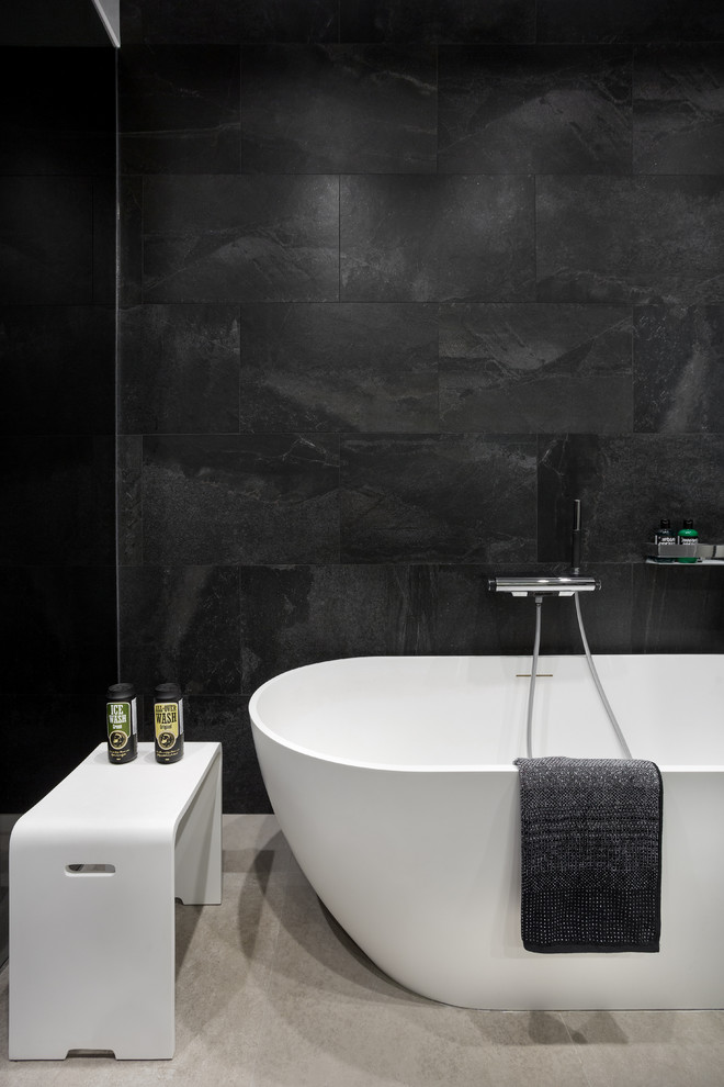 На фото: ванная комната в современном стиле с отдельно стоящей ванной и черной плиткой