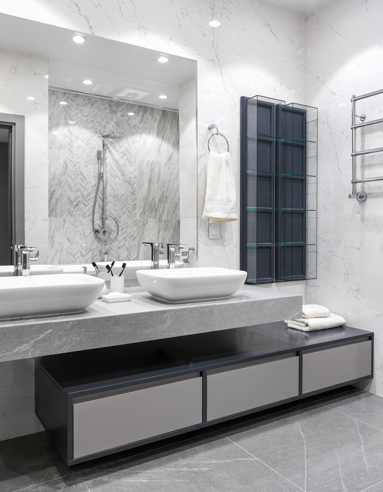 Cette photo montre une salle de bain tendance avec un placard à porte plane, des portes de placard grises, un carrelage blanc, une vasque, un sol gris et un plan de toilette gris.
