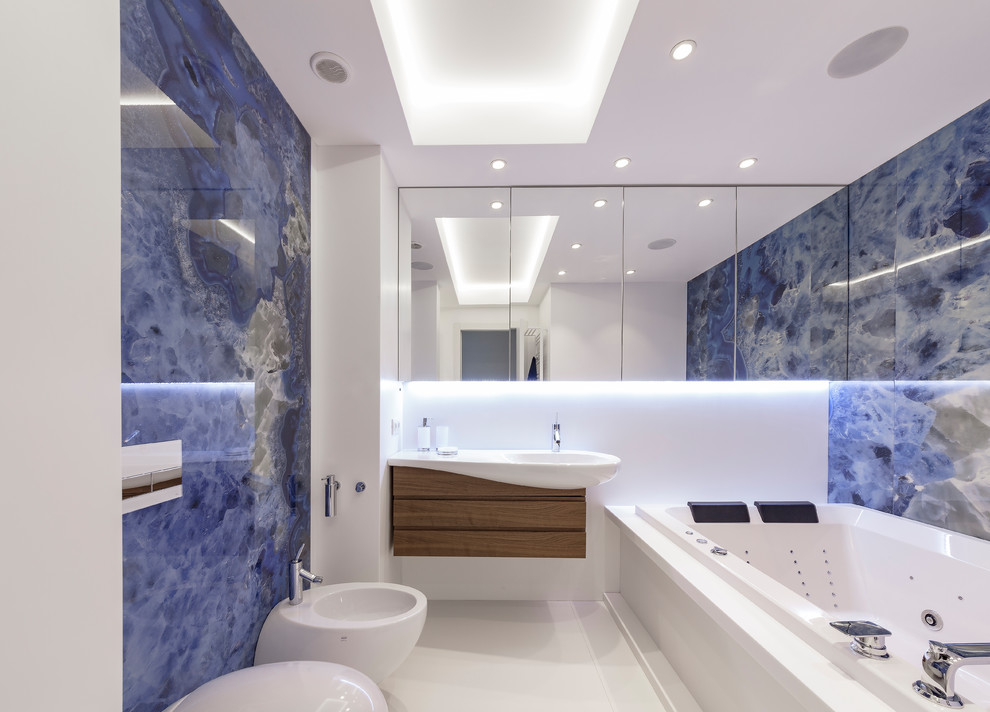 Foto på ett mellanstort funkis en-suite badrum, med en jacuzzi, blå kakel, vita väggar, klinkergolv i porslin, vitt golv, släta luckor, skåp i mellenmörkt trä, en bidé och ett konsol handfat