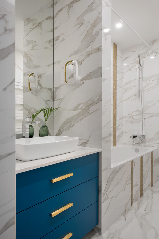 Exempel på ett mellanstort modernt vit vitt en-suite badrum, med släta luckor, vit kakel, keramikplattor, klinkergolv i porslin, bänkskiva i kvarts, vitt golv, blå skåp och ett fristående handfat