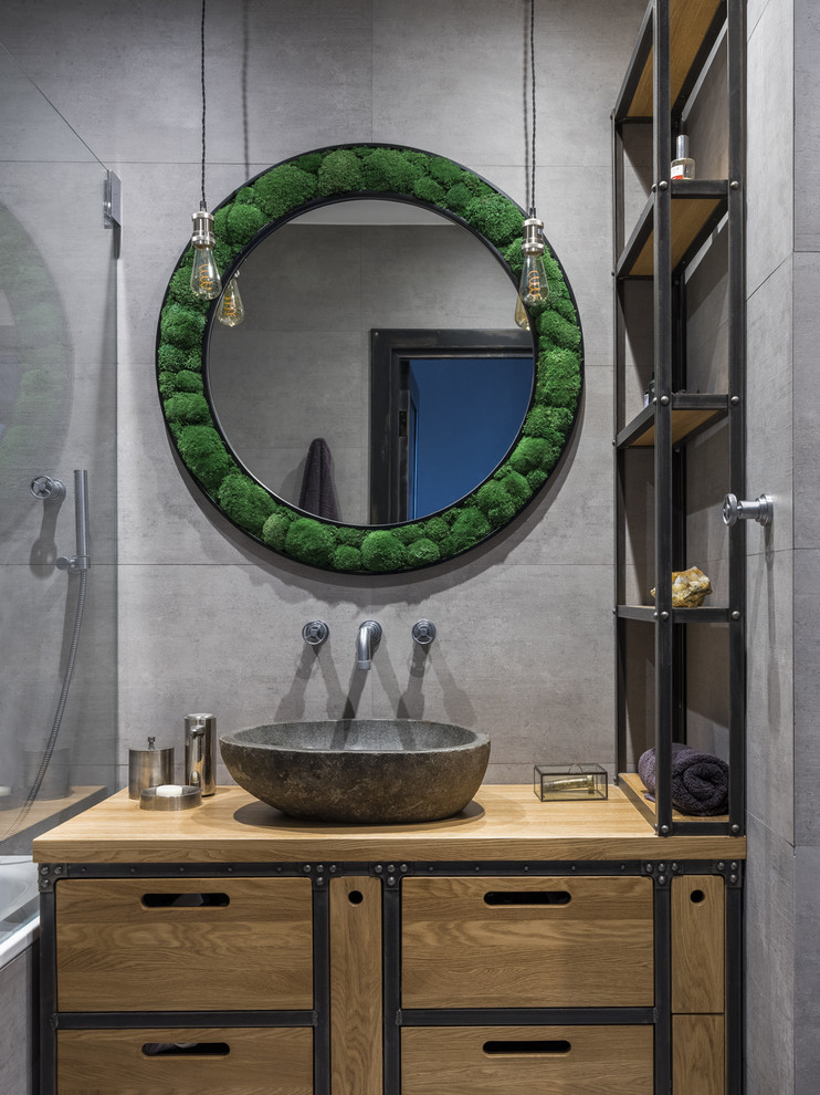 Imagen de cuarto de baño principal urbano con armarios con paneles lisos, puertas de armario de madera oscura, baldosas y/o azulejos grises, lavabo sobreencimera, encimera de madera y encimeras marrones