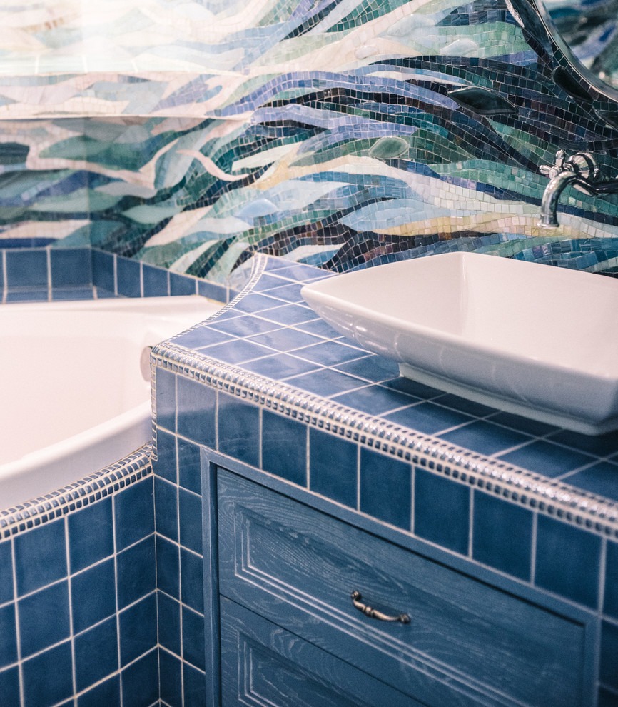 Пример оригинального дизайна: главная ванная комната в современном стиле с фасадами с утопленной филенкой, синими фасадами, угловой ванной, настольной раковиной, столешницей из плитки и синей столешницей