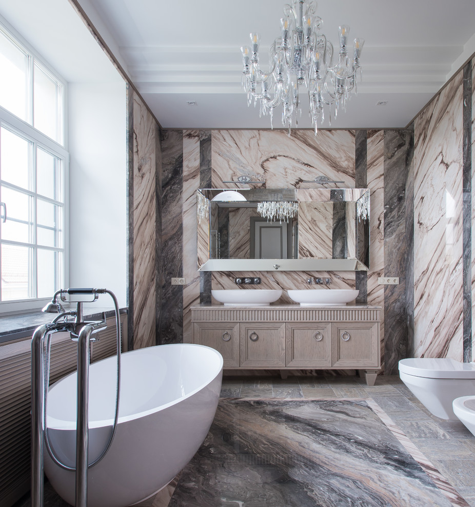 Klassisk inredning av ett beige beige badrum med dusch, med beige skåp, ett fristående badkar, en vägghängd toalettstol, ett fristående handfat, flerfärgat golv och luckor med infälld panel