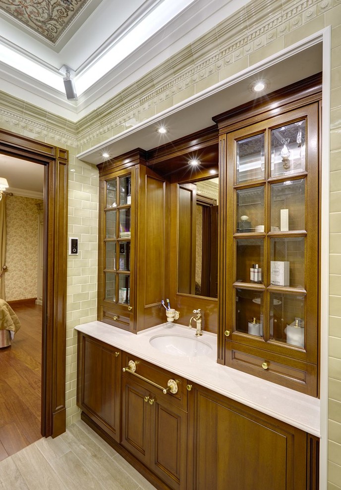 Foto de cuarto de baño clásico con puertas de armario de madera oscura, baldosas y/o azulejos beige, lavabo bajoencimera y armarios con paneles con relieve