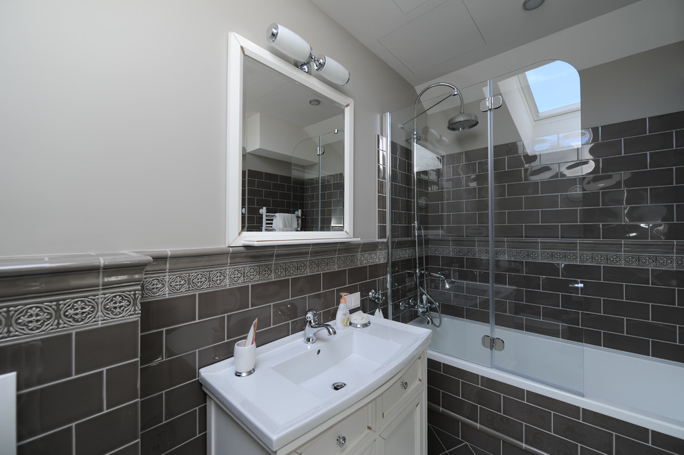 Inspiration for a medium sized classic ensuite bathroom in Moscow with a shower/bath combination, metro tiles, grey walls, an alcove bath, shaker cabinets, beige cabinets, a wall mounted toilet, brown tiles, porcelain flooring, a built-in sink, grey floors, a shower curtain and white worktops.