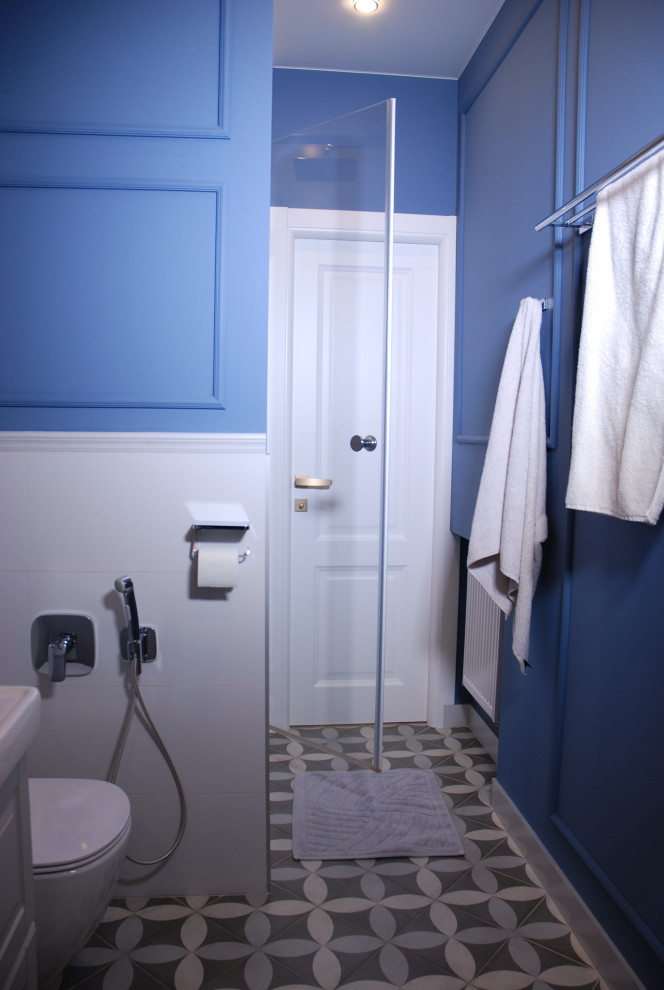 Idée de décoration pour une salle de bain tradition de taille moyenne avec des portes de placard grises, une baignoire encastrée, WC suspendus, un carrelage gris, des carreaux de porcelaine, un mur bleu, un sol en carrelage de porcelaine, un lavabo posé, un sol gris et une cabine de douche à porte battante.