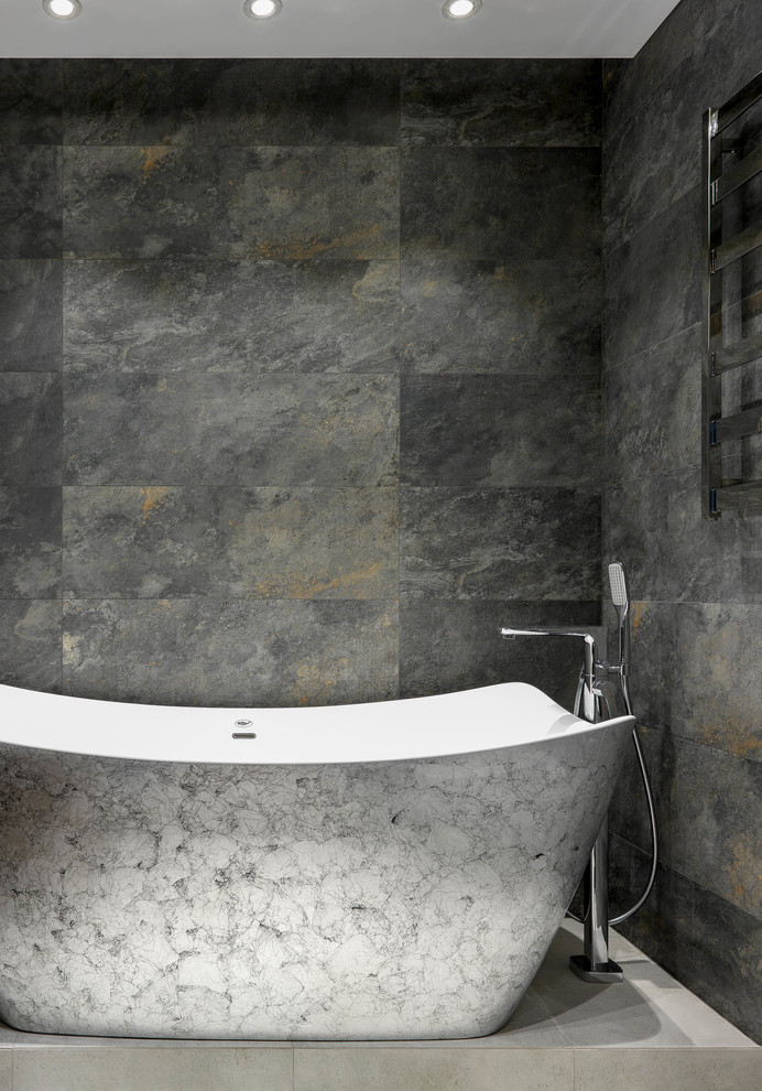 Aménagement d'une salle de bain principale contemporaine de taille moyenne avec une baignoire indépendante, WC suspendus, un carrelage gris, des carreaux de porcelaine, un sol en carrelage de porcelaine, un plan de toilette en surface solide et un sol gris.
