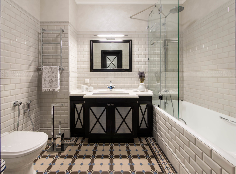 На фото: главная ванная комната в стиле неоклассика (современная классика) с черными фасадами, ванной в нише, душем над ванной, раздельным унитазом, бежевой плиткой, накладной раковиной и разноцветным полом