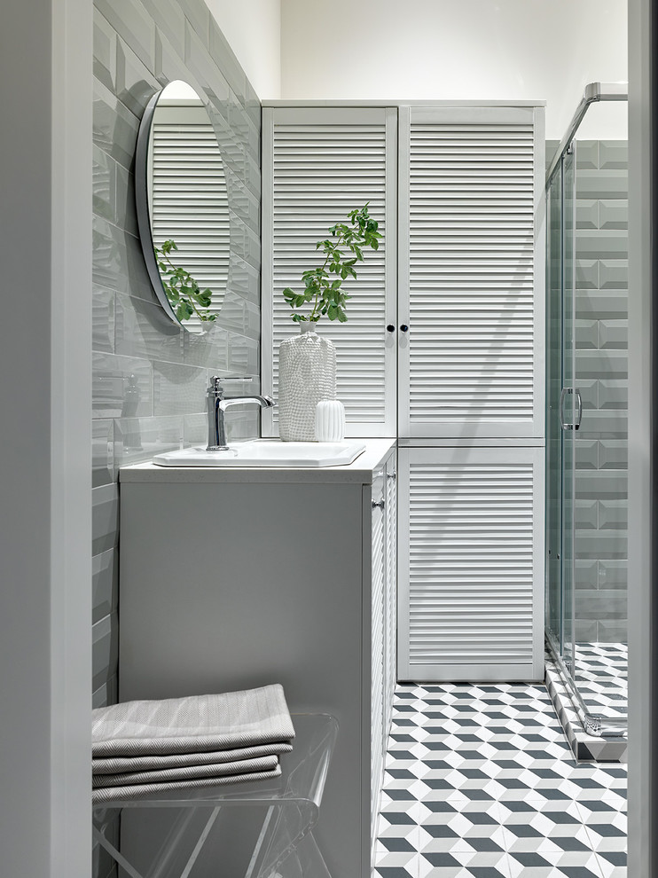 Immagine di una stanza da bagno con doccia contemporanea con ante a persiana, ante bianche, lavabo da incasso, pavimento multicolore e top bianco