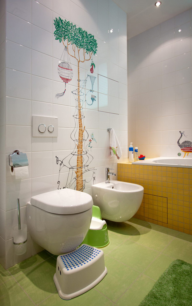 Réalisation d'une salle de bain bohème de taille moyenne pour enfant avec un placard à porte plane, des portes de placard rouges, une baignoire posée, WC suspendus, un carrelage multicolore, des carreaux de céramique, un mur multicolore, un sol en carrelage de céramique, un lavabo suspendu, un plan de toilette en verre, un sol vert et un plan de toilette blanc.
