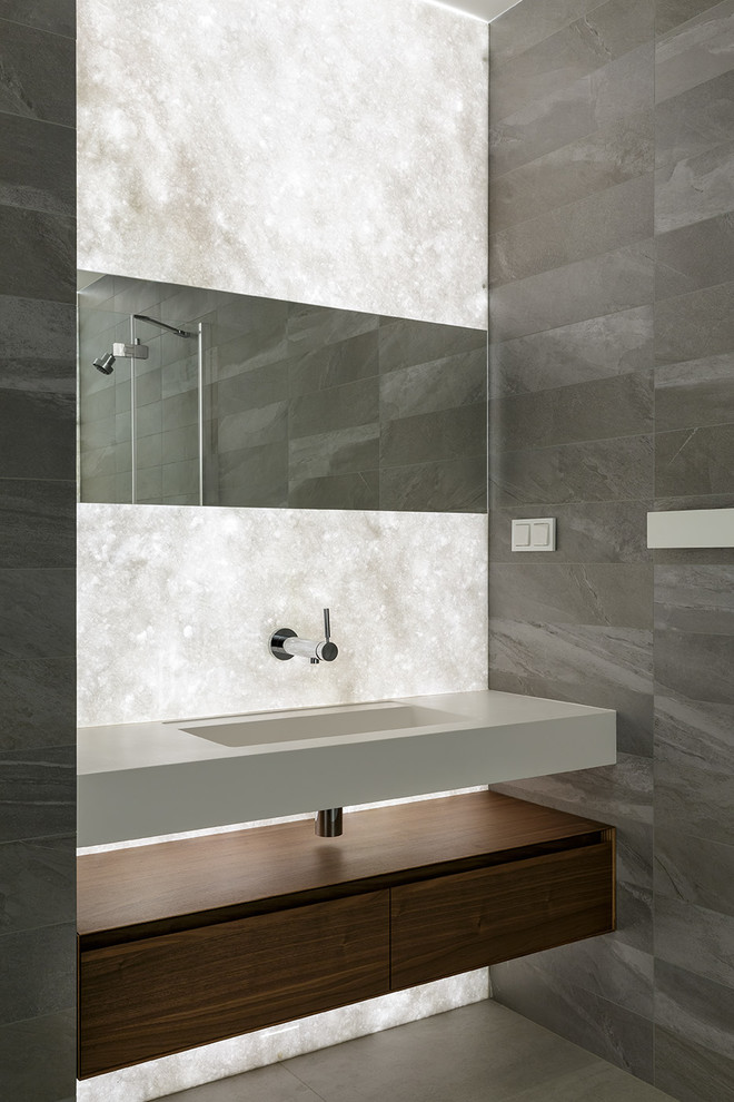 На фото: ванная комната в современном стиле с серой плиткой, монолитной раковиной и серым полом